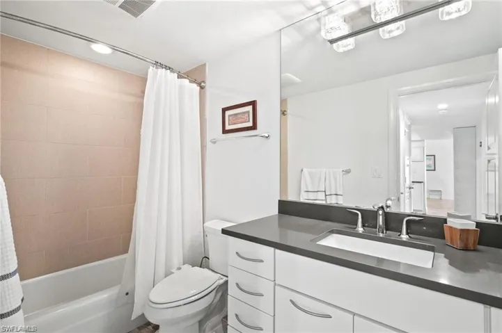 Full bathroom featuring shower / bathtub combination with curtain, toilet, and oversized vanity