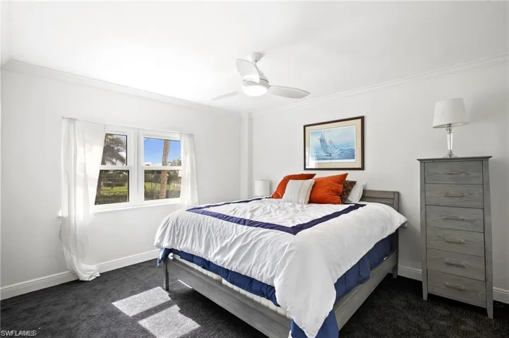 Carpeted bedroom featuring ornamental molding and ceiling fan