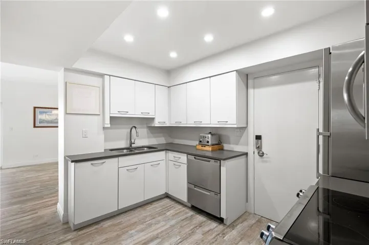 Kitchen featuring appliances with stainless steel finishes, light hardwood / wood-style floors, sink, and white cabinetry