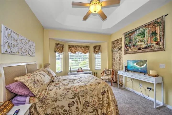 Bedroom featuring carpet flooring, ceiling fan, and a raised ceiling