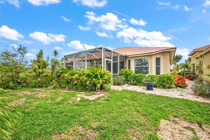 Rear view of house with glass enclosure and a lawn