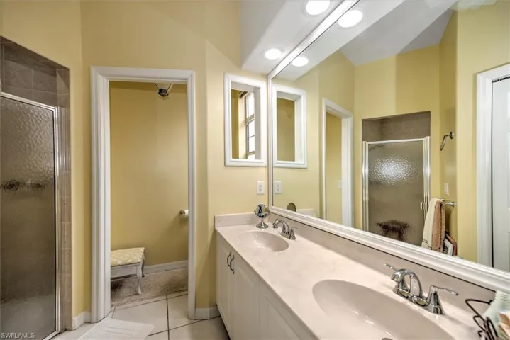 Bathroom with tile floors, a shower with shower door, and double sink vanity