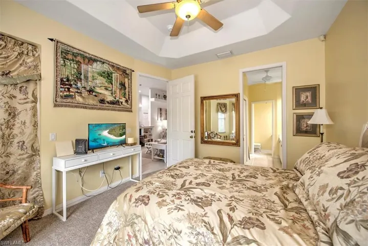 Bedroom featuring carpet, ceiling fan, and a raised ceiling