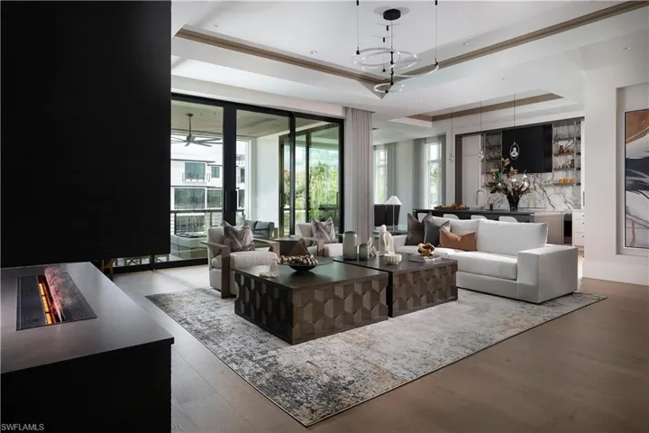 Living room featuring a raised ceiling, plenty of natural light, and wood finished floors