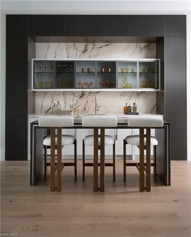 Indoor bar with light wood finished floors, backsplash, and range hood
