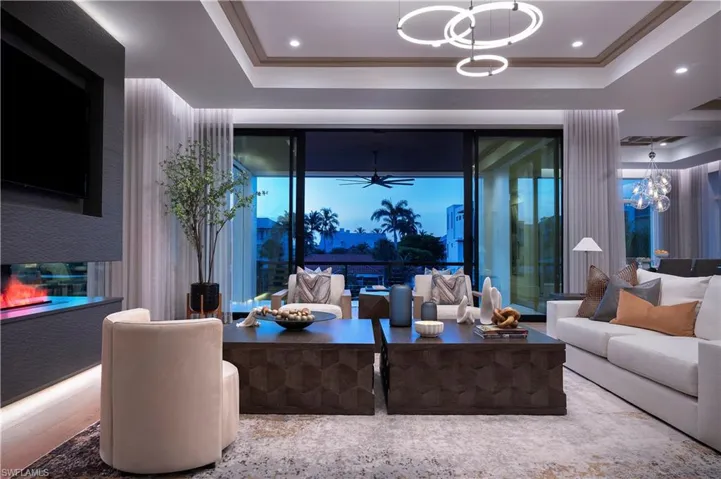 Living room with a tray ceiling, a chandelier, and a ceiling fan