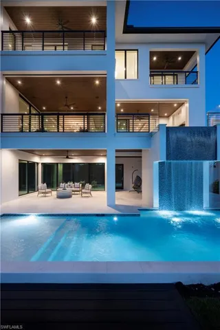 Back of property featuring a balcony, an outdoor hangout area, ceiling fan, a patio area, and an outdoor pool