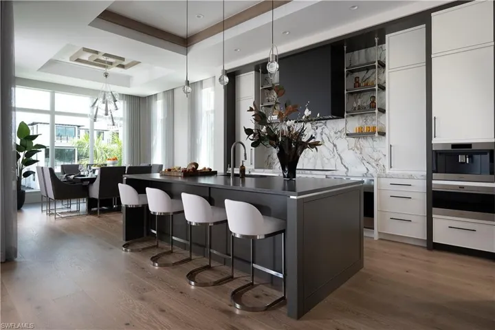Kitchen with a breakfast bar, a tray ceiling, open shelves, dark countertops, and dark wood-style flooring