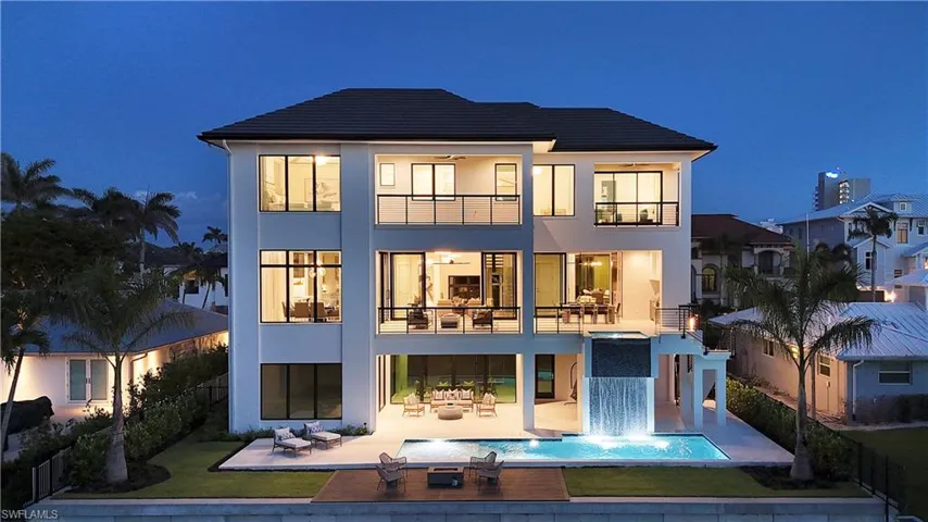 Back of house at twilight featuring a balcony, stucco siding, a patio, and an outdoor pool