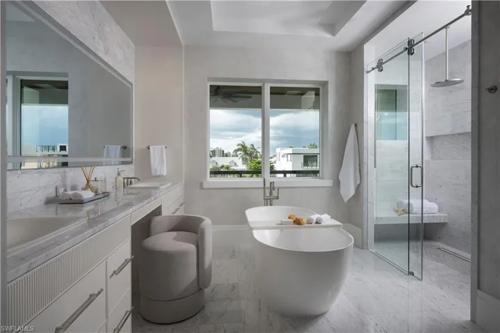 Full bath with a stall shower, double vanity, a freestanding bath, marble look tile flooring, and ceiling fan