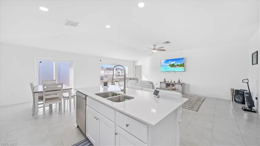 Kitchen featuring white cabinetry, open floor plan, an island with sink, recessed lighting, and stainless steel dishwasher