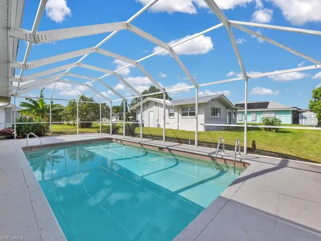 Swimming pool with glass enclosure, a sunroom, a yard, and a patio area