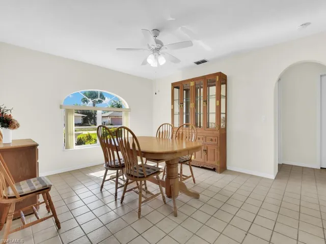 Dining area with arched walkways, a ceiling fan, and light tile patterned floors
