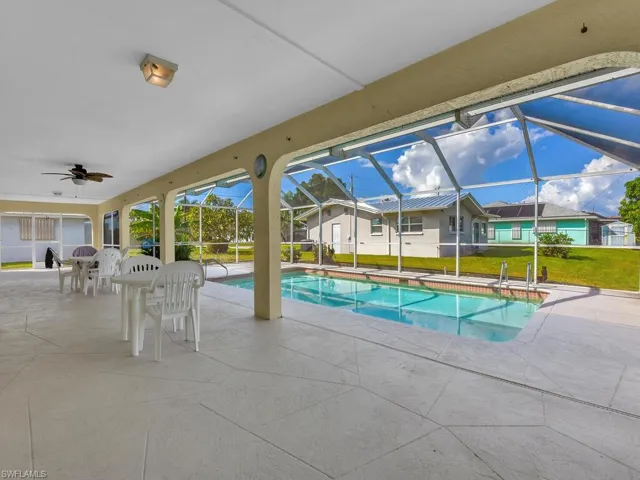 Swimming pool featuring a patio, a lawn, a ceiling fan, and screen enclosure