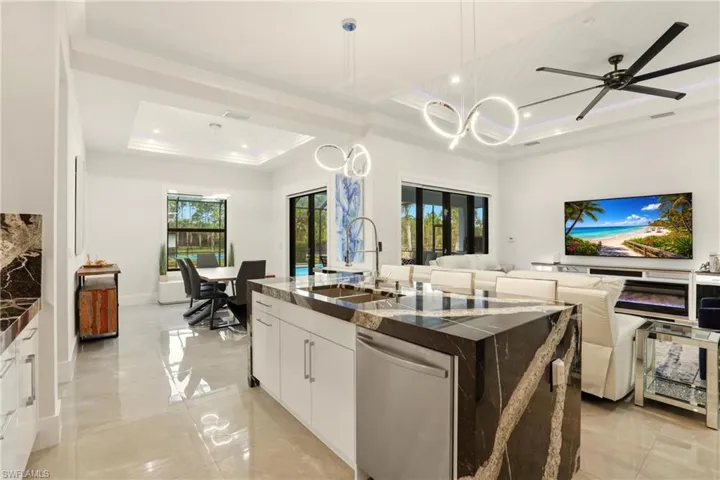 Kitchen featuring white cabinets, dishwasher, dark stone countertops, open floor plan, and modern cabinets