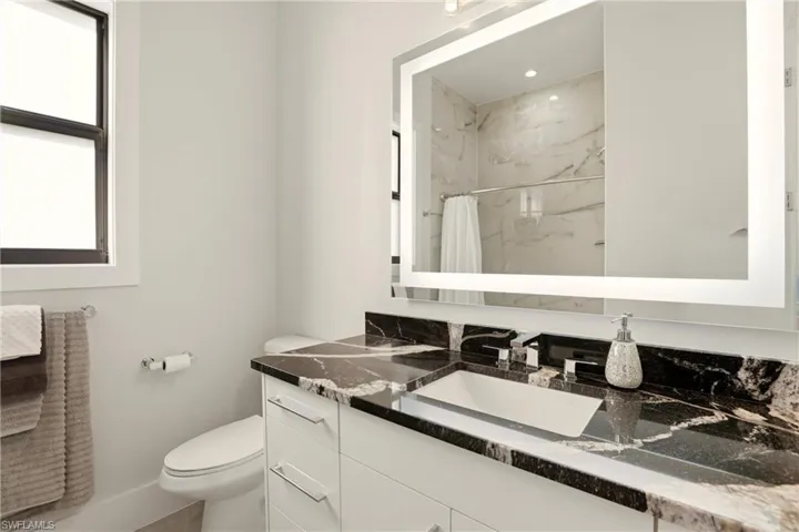 Full bath featuring a marble finish shower and vanity