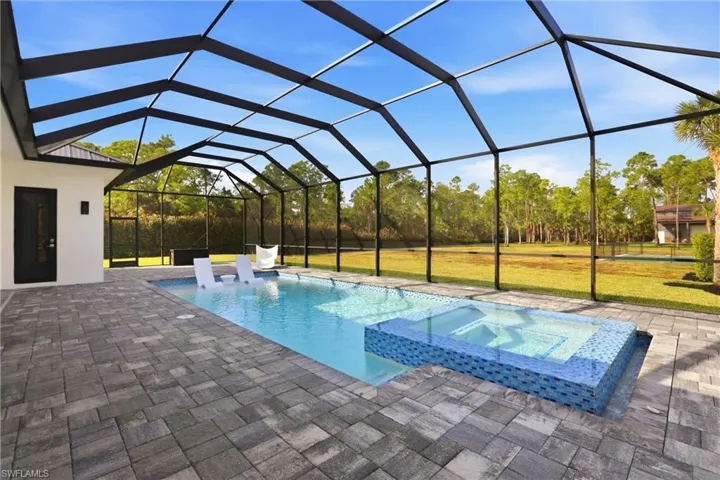 Relaxing pool / spa featuring a sunroom, a lanai, a patio area, and a yard