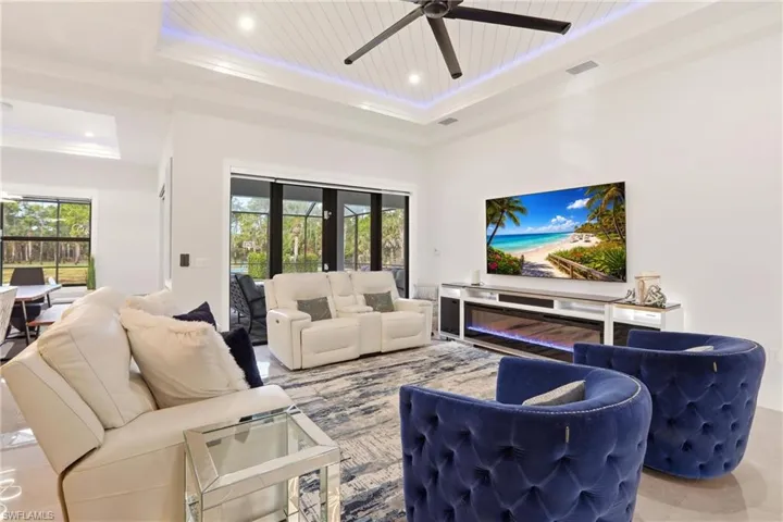 Living area with plenty of natural light, a ceiling fan, tile patterned floors, a wood tray ceiling, and recessed lighting