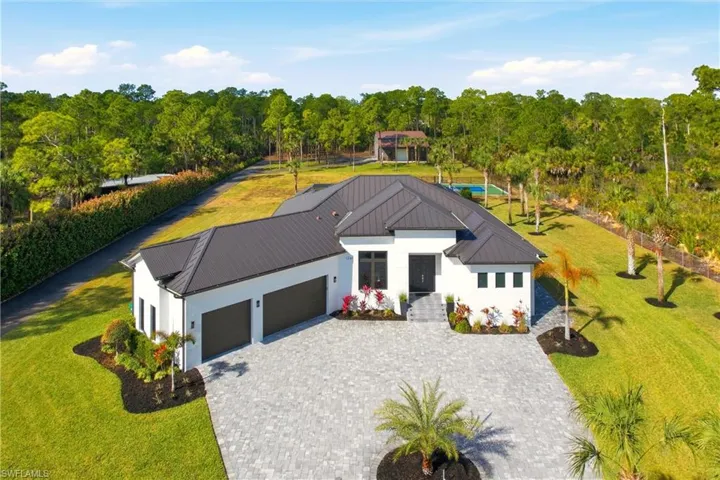 View of front of property with a front yard, an attached garage, and decorative driveway