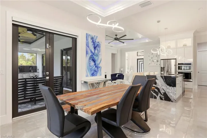 Dining area with crown molding, ceiling fan, a raised ceiling, and hanging lights