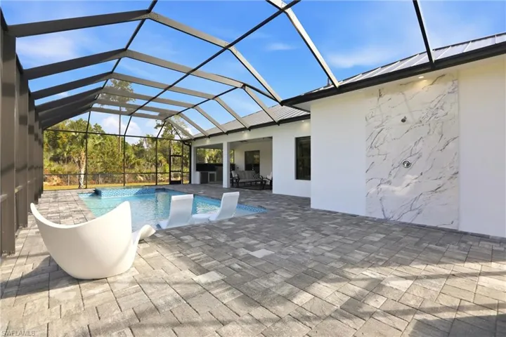 Outdoor pool with a sunroom, glass enclosure, and a patio