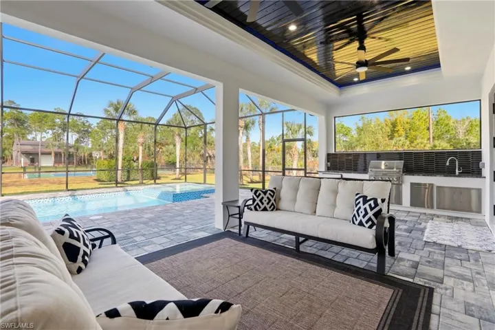 View of patio with an outdoor kitchen with living area, a lanai, a sunroom, and a ceiling fan