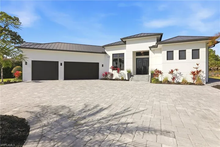 Prairie-style home featuring a standing seam roof, stucco siding, decorative driveway, and an attached garage