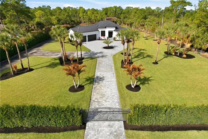 View of front of house featuring decorative driveway, a front yard, a garage, and view of scattered trees