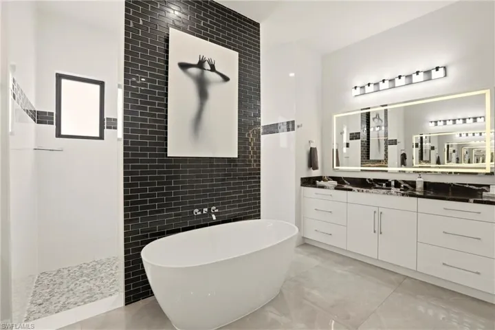 Full bathroom with tile walls, vanity, a freestanding tub, and walk in shower