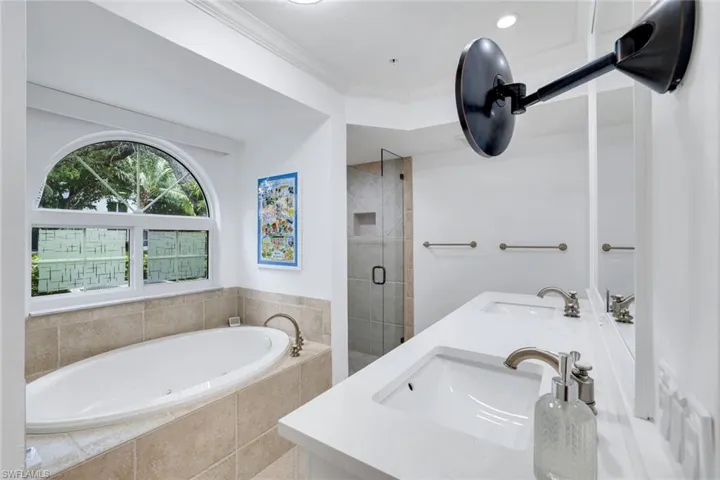 Full bath with a stall shower, a jetted tub, double vanity, and crown molding