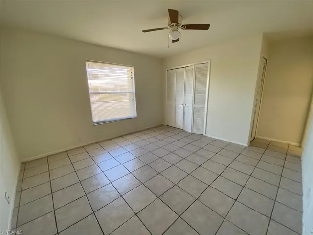Unfurnished bedroom with light tile patterned floors, a closet, and ceiling fan