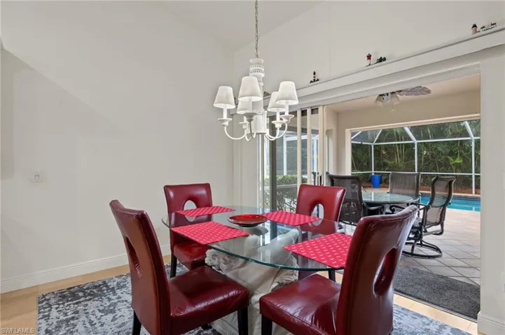Dining space with an inviting chandelier, light hardwood / wood-style floors, and high vaulted ceiling
