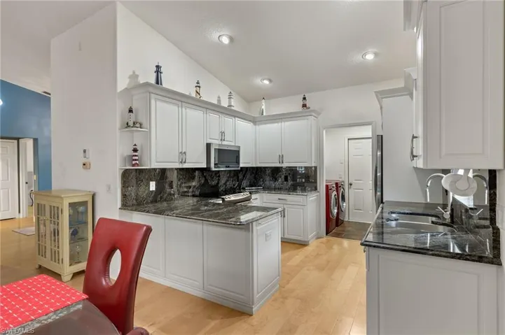 Kitchen featuring white cabinetry, sink, independent washer and dryer, appliances with stainless steel finishes, and light wood-type flooring