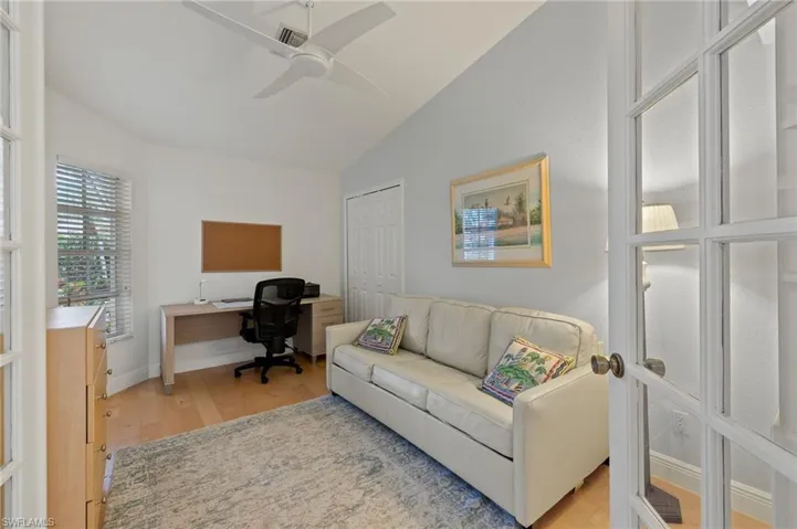 Home office featuring ceiling fan, light wood-type flooring, and vaulted ceiling