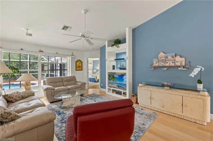 Living room with hardwood / wood-style floors, ceiling fan, and lofted ceiling