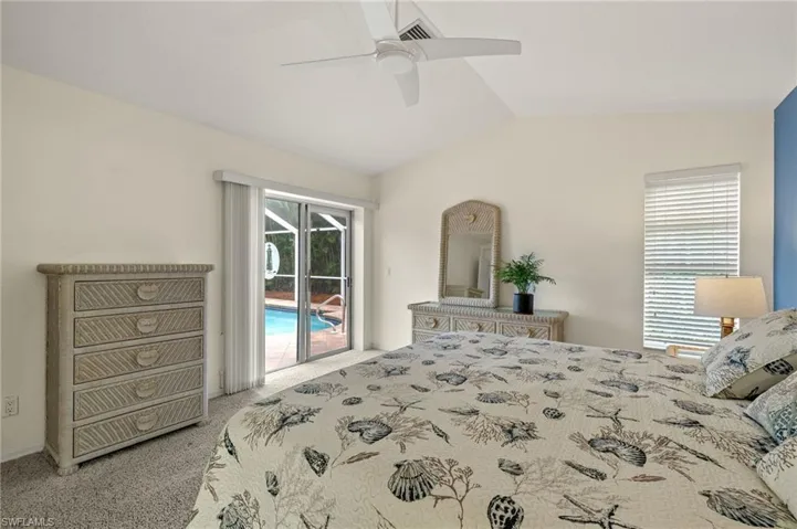 Carpeted bedroom with access to outside, multiple windows, ceiling fan, and vaulted ceiling