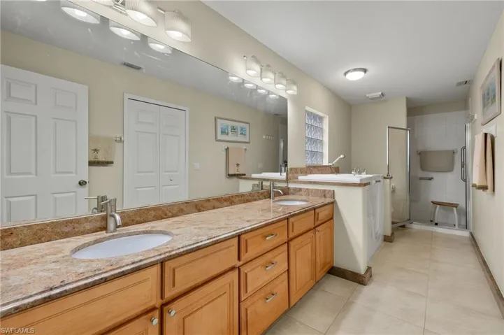 Bathroom featuring tile patterned flooring, vanity, and walk in shower