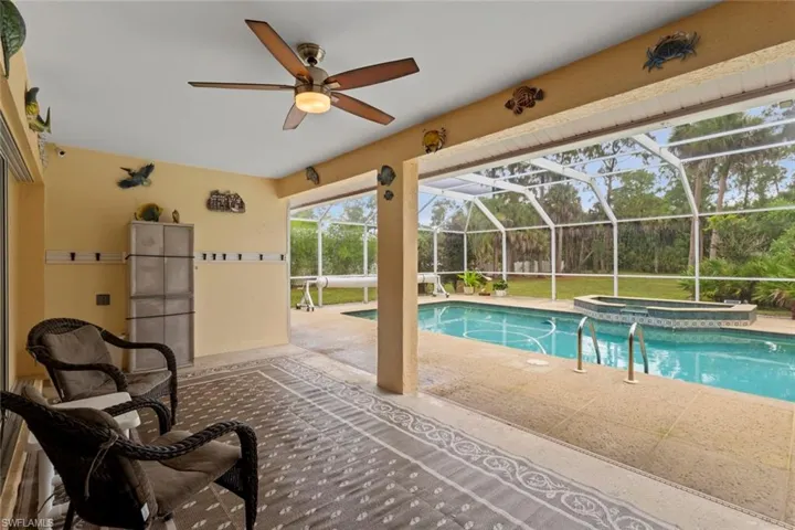 Screened lanai featuring outdoor shower, ceiling fan, and direct access to the outdoor pool area with a hot tub
