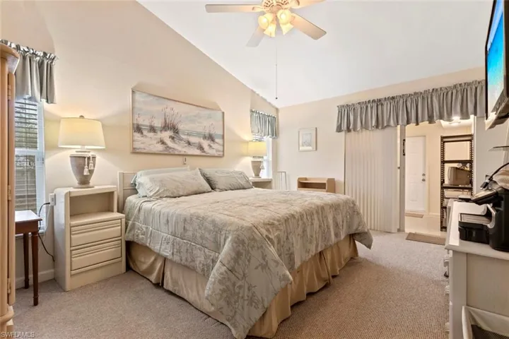 Master carpeted bedroom featuring vaulted ceilings, a ceiling fan with integrated lighting, and a window with horizontal blinds
