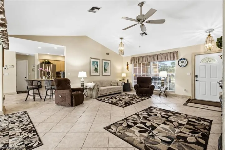 Spacious living area featuring vaulted ceilings, ceiling fan, and tiled flooring