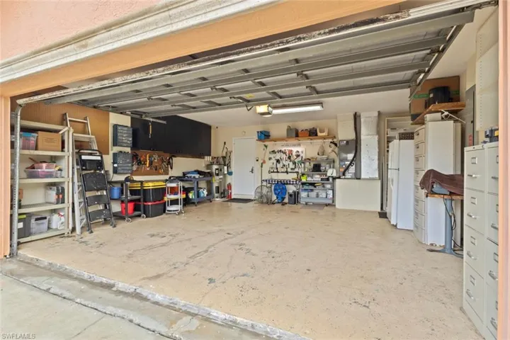 Spacious two car garage featuring an overhead door, concrete flooring, overhead lighting, and built-in cabinets.