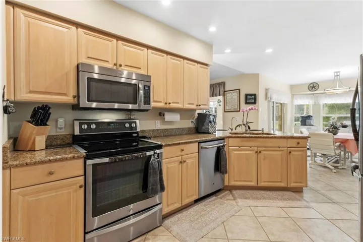 Kitchen featuring light wood-finish cabinetry, stainless steel appliances, granite countertops, and recessed lighting