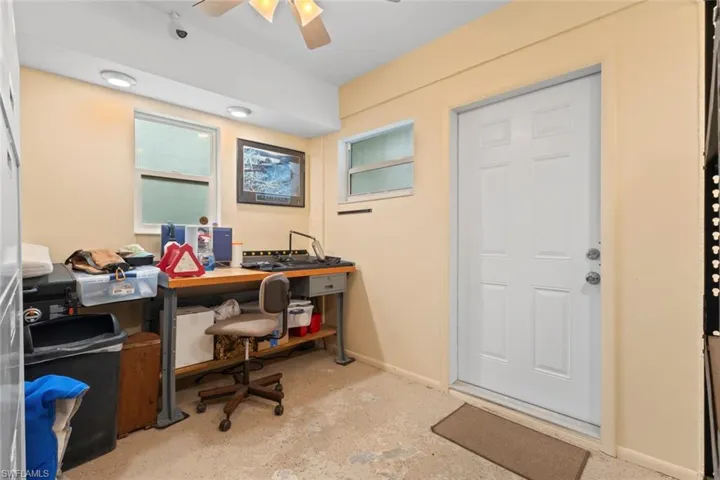 Den/Office is attached to the master bedroom room featuring a white paneled door, multiple windows, light-toned walls, and a ceiling fan with integrated lighting
