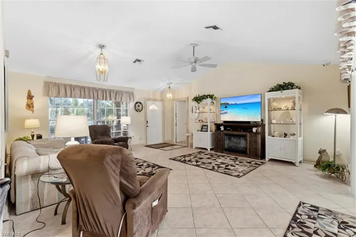 Spacious interior featuring neutral tile flooring, vaulted ceilings, and a ceiling fan
