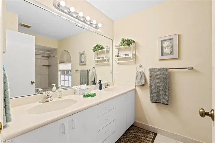 Master bathroom with dual sink vanity with ample countertop space, white cabinetry, and a large wall-mounted mirror with overhead bar lighting
