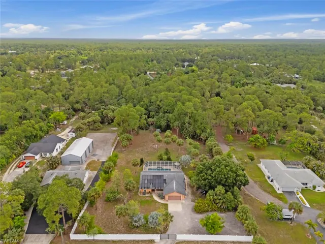 Main residence featuring a screened-in pool enclosure, an attached garage, and a gravel driveway
