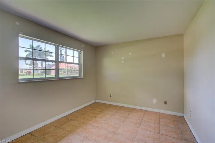 Empty room with baseboards and light tile patterned flooring