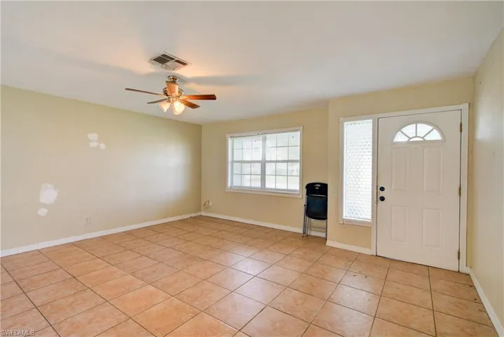 Foyer entrance with light tile patterned flooring and a ceiling fan