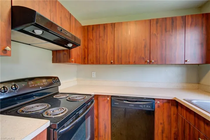 Kitchen featuring black appliances, range hood, and light countertops