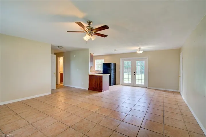 Unfurnished living room with light tile patterned floors, french doors, and ceiling fan